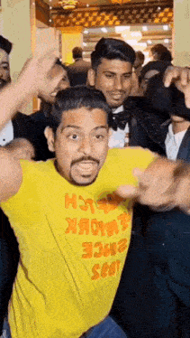a man in a yellow t-shirt is dancing in a crowd .