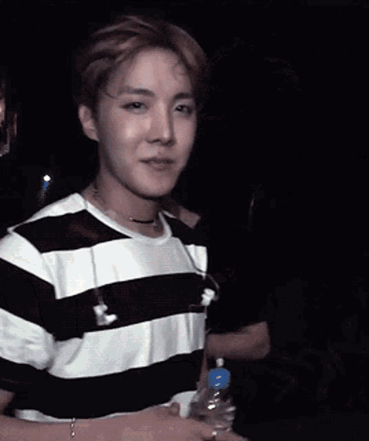 a man in a black and white striped shirt holds a bottle of water