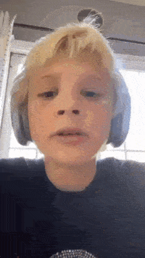 a young boy with blonde hair is wearing headphones