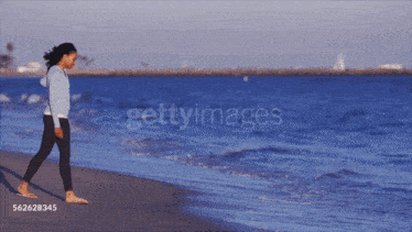 a woman standing on a beach with the word getty images on the bottom right