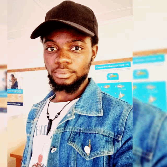 a man wearing a hat and a denim jacket is standing in front of a poster that says coronavirus disease