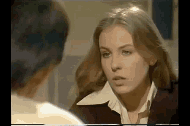a woman is talking to a man in a room and looking at him .