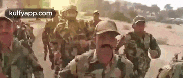 a group of soldiers are marching down a road .