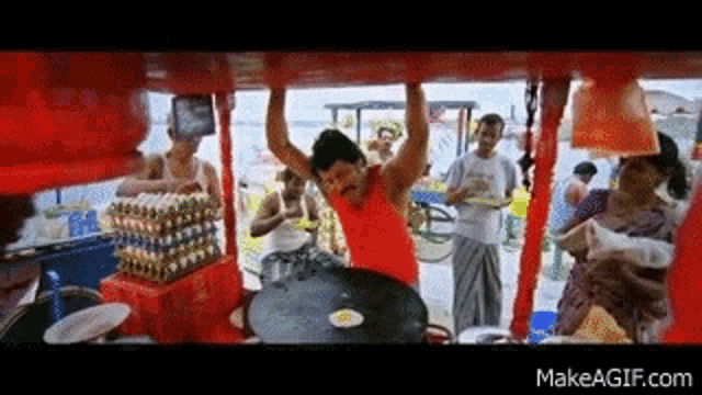 a man in a red tank top is hanging from the ceiling of a cart .