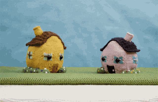 two knitted houses are sitting on a green rug