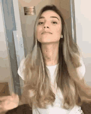 a woman with long blonde hair wearing a white shirt