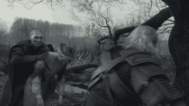 a man is holding a dog while another man stands behind him