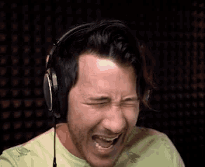 a man wearing headphones is laughing with his eyes closed and his mouth open .