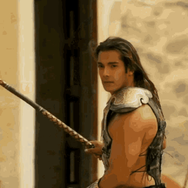 a naked man with long hair is holding a spear