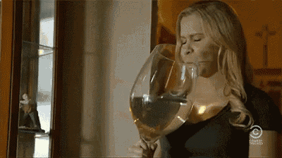 a woman is drinking from a large wine glass .