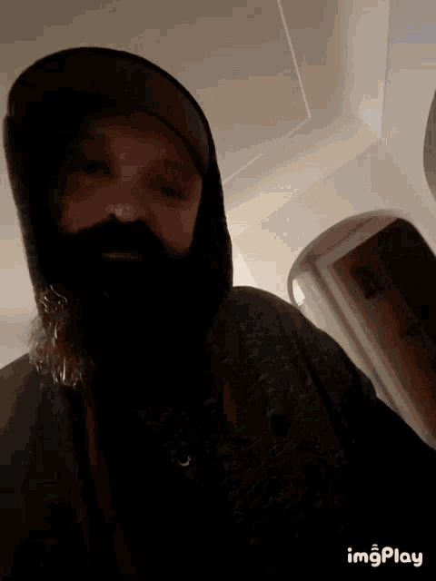 a man with a beard is wearing a hooded jacket and a hat