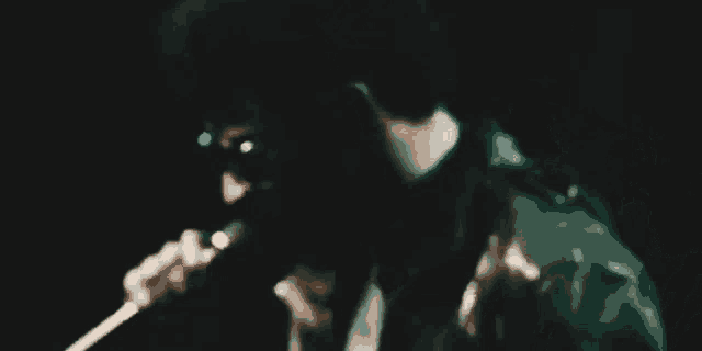 a man is singing into a microphone in the dark