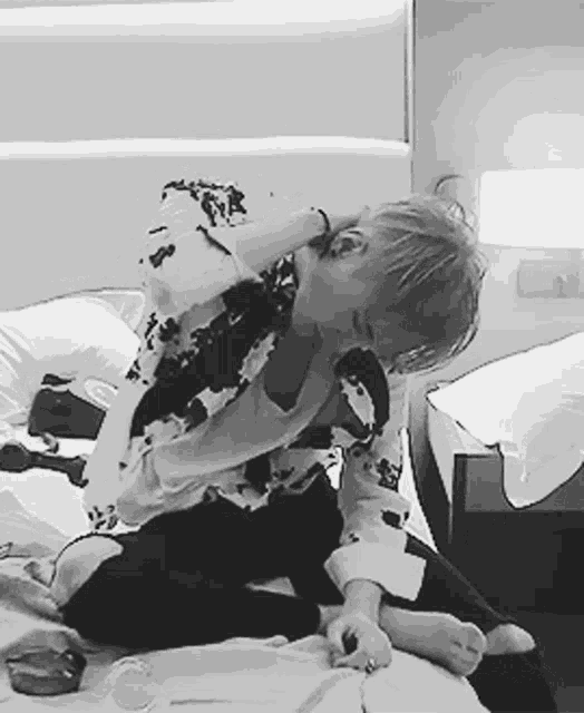 a person is sitting on a bed with their hands on their neck