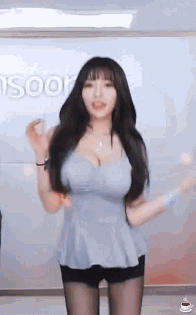 a woman in a blue top and black shorts is dancing on a webcam .
