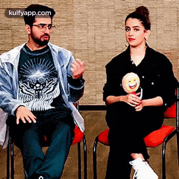 a man and a woman are sitting in chairs talking to each other .