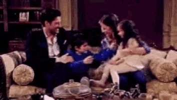 a family is sitting on a couch in a living room and laughing .