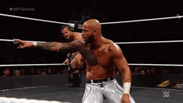 two wrestlers in a wrestling ring with the words nxt take over on the bottom