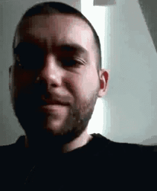 a man with a beard wearing a black shirt is smiling