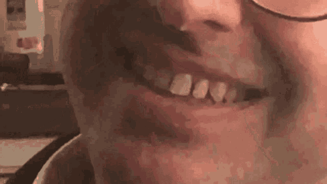 a close up of a man 's mouth with glasses and a missing tooth .