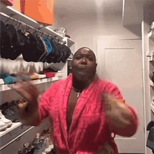 a man in a pink robe is standing in a closet full of hats