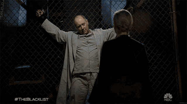a man and a woman are behind a chain link fence with the nbc logo on the bottom