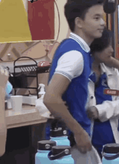 a man in a blue shirt is standing next to a woman in a white shirt holding a blue water bottle