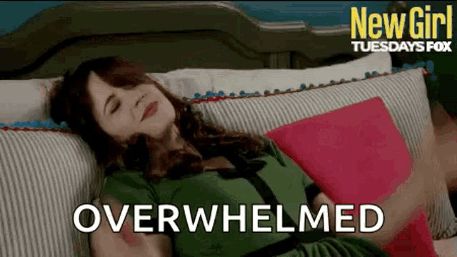 a woman in a green dress is laying on a couch with a pink pillow and the words overwhelmed .
