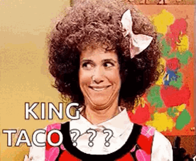 a woman with a big afro and a bow in her hair is making a funny face .