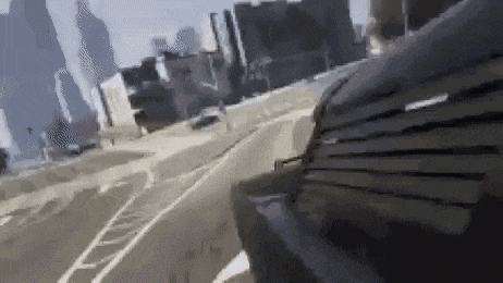 a person is sitting on a bench on the side of a road in front of a city .