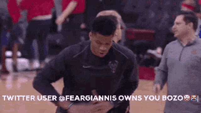 a man is standing on a basketball court with the words twitter user @feargiannis owns you bozo on the bottom