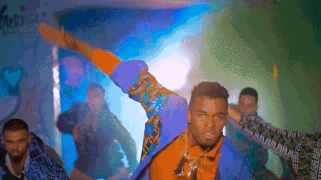 a group of people are dancing in a room with graffiti on the wall behind them