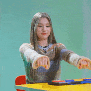 a girl is sitting at a table with her hands in the air and a sign that says ' n ' on it
