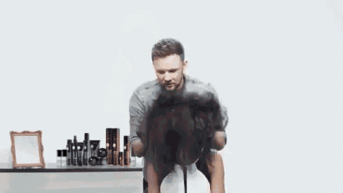 a man is holding a woman 's hair in a salon .
