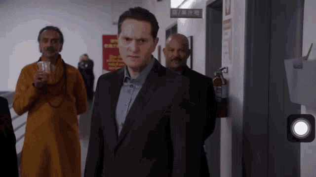 a man in a suit stands in a hallway with a fire extinguisher