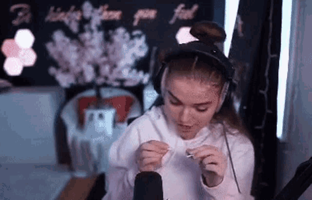 a woman wearing headphones is smoking a cigarette in front of a microphone in a room .