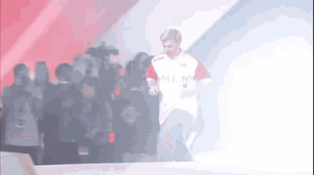 a man in a white shirt with the word men on it is walking on a stage
