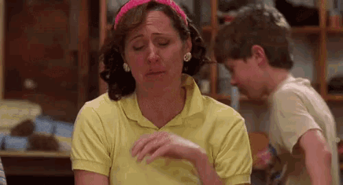 a woman in a yellow shirt is crying while sitting at a table .
