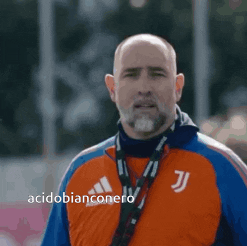 a bald man with a beard is wearing an orange jacket with the letter j on it