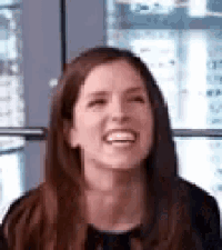 a woman with long brown hair is smiling and laughing .