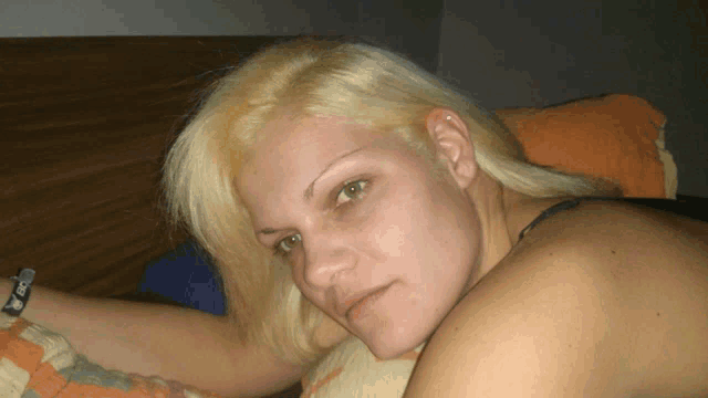 a woman with blonde hair and green eyes is laying down