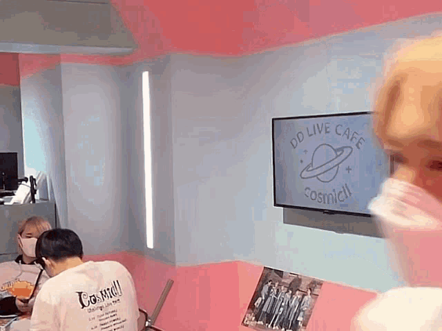 a man in a white shirt is sitting in front of a tv that says dd live cafe cosmidl