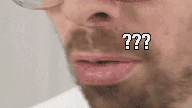 a man with a beard and glasses is making a funny face with a question mark on his mouth .