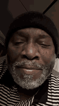 a man with a beard is wearing a black beanie and striped shirt