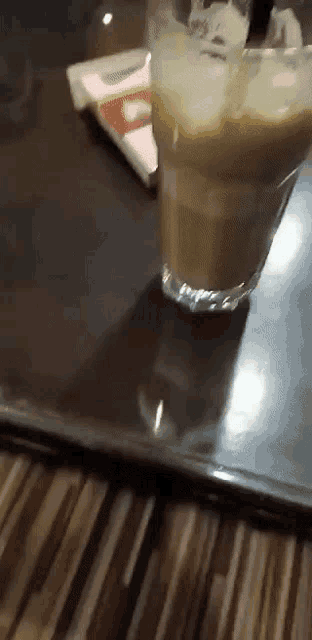 a glass of milkshake with a straw on a wooden table