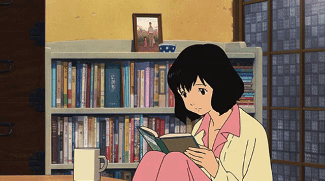 a girl sits at a table reading a book