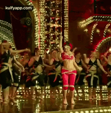 a group of people are dancing on a stage in a room .
