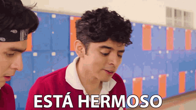two men are standing in front of lockers and one of them says esta hermoso