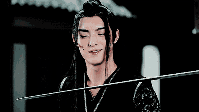 a man with long hair is holding a sword and smiling with his eyes closed