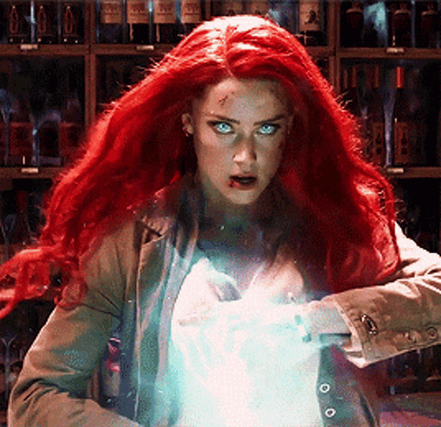 a woman with red hair is standing in front of a shelf with bottles of alcohol