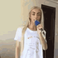 a blonde woman is singing into a blue microphone .